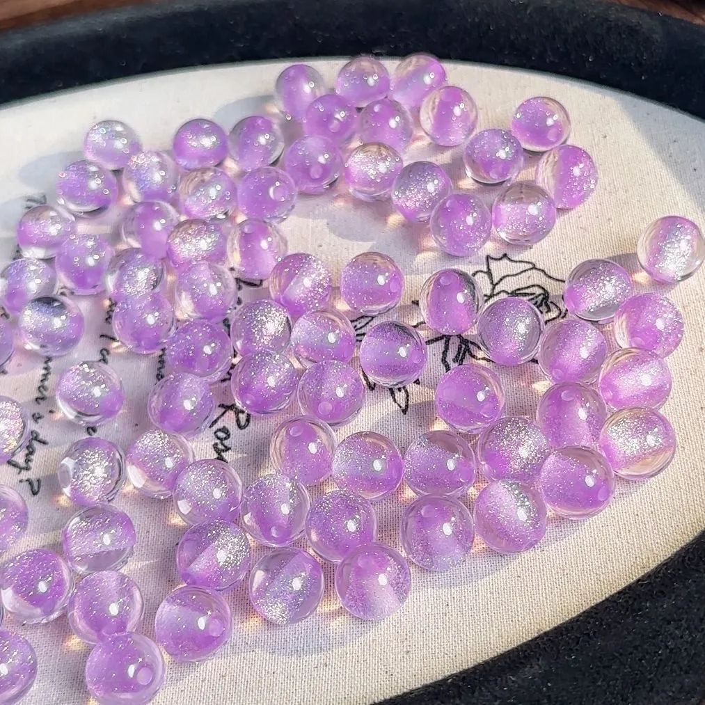 16mm round plastic scattered beads with glittering cat's eye effect in champagne colour, on a white background.