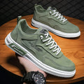 Men's green canvas lace-up sneakers with round toe, flat heel, and letter print side detail on a white background