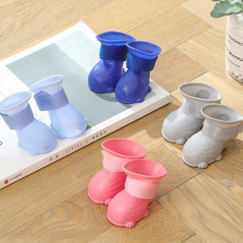 Set of four waterproof silicone dog rain boots in dark blue, gray, light blue, and pink on a white background