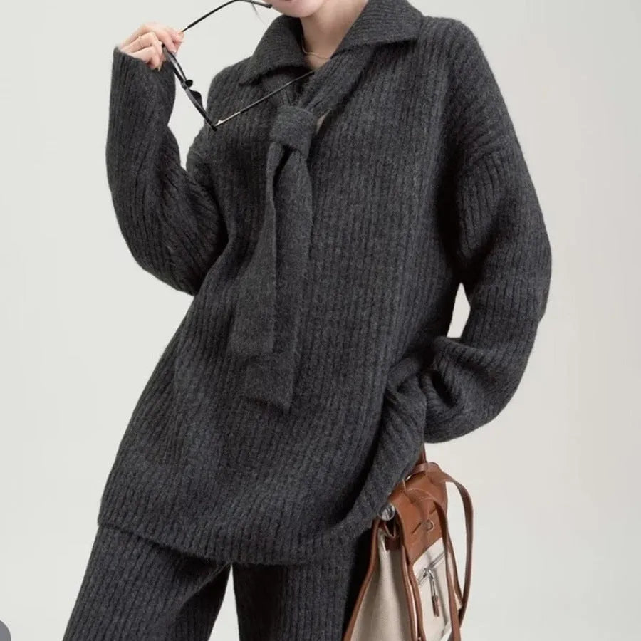 Beige women's knitted acrylic sweater and trouser two-piece set laid flat.