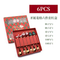 Stainless steel Christmas spoon and fork set with festive handle designs on a red background.