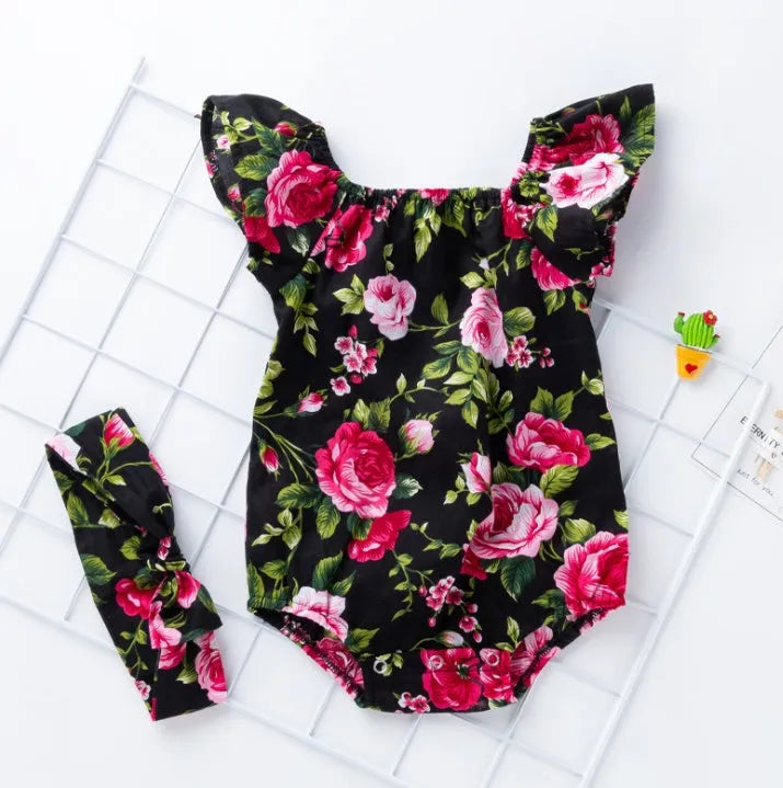 Baby girl in a black cotton romper with small flying sleeves print, showing sleeveless triangle climbing style.