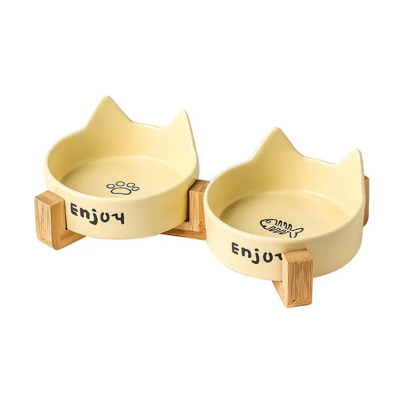 Porcelain cat bowl in a wooden anti-tip frame, showing cat's paw print design in pink.