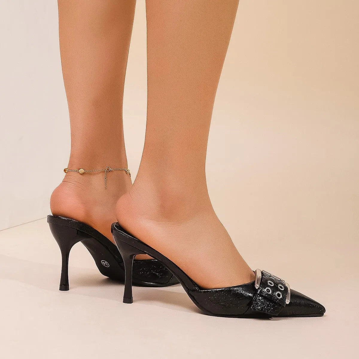 Black women's high heel shoes with pointed toe and buckle strap decoration.