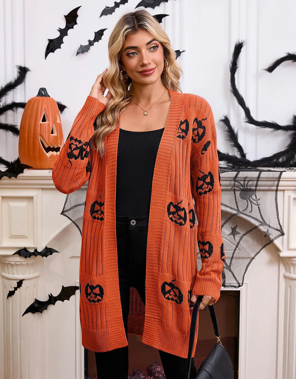 Women's black knitted cardigan with an orange jacquard pumpkin head pattern on the front.