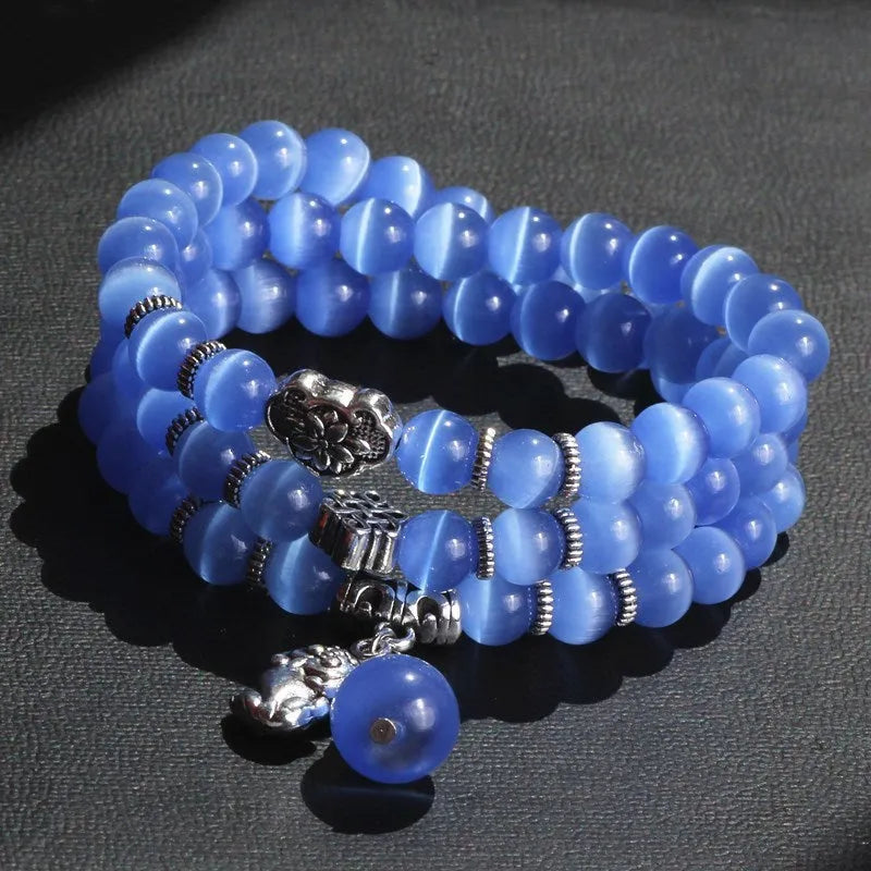 Women's opal bracelet with lucky cat charm, shown in a triple-wrap style with colourful geometric beads.