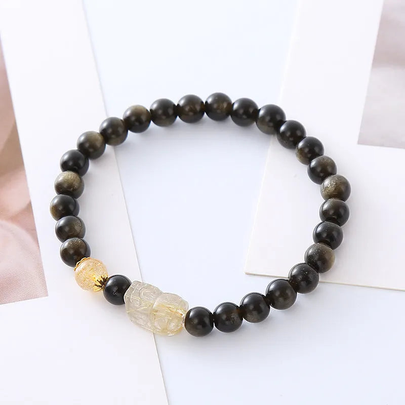 Handcrafted natural obsidian Pi Xiu bracelet with gold and red design on wrist