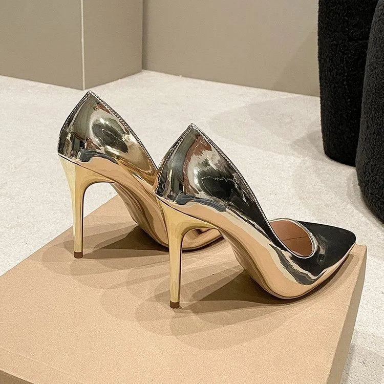 Gold and silver pointed toe slip-on stiletto heel pumps on a plain background