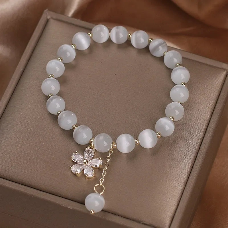 Single loop white cat's eye crystal bracelet with flower tassels and a morganite safety buckle pendant.
