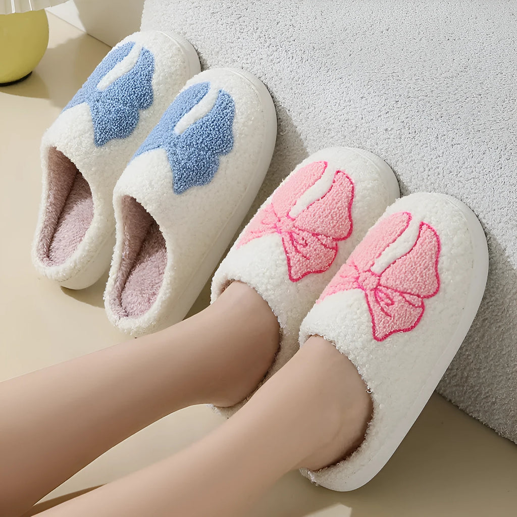 A pair of pink cartoon bow knot suede slippers with a TPR sole, shown from the side.