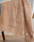 Set of three cotton towels in beige and brown including large bath towel, hand towel, and small washcloth