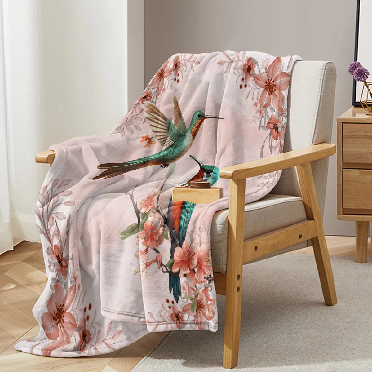Pink hummingbird floral fleece throw blanket on sofa with floral print