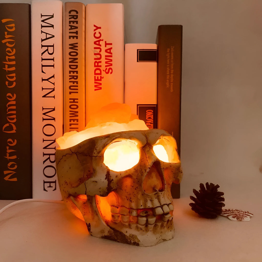 Skull-shaped Himalayan crystal salt lamp with USB dimmable LED showing warm amber light on a resin base