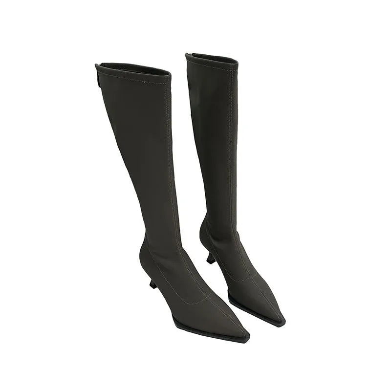 Black pointed-toe below-knee women's boots with a stiletto heel and a visible back zip on a neutral background.