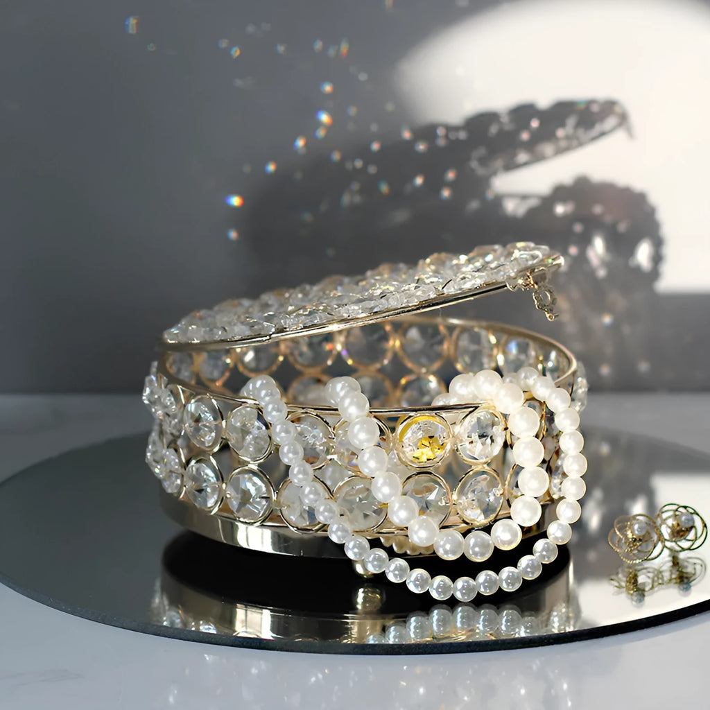 Transparent crystal glass jewelry storage box with a French gold-coloured metal frame on a table.