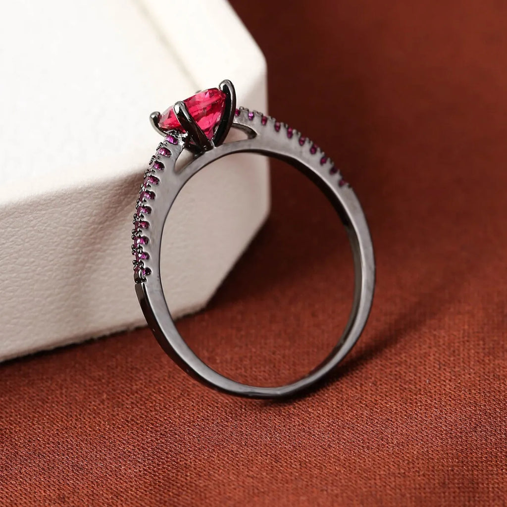 A geometric hexagonal copper ring with a central zircon stone, shown in a gun black and rose red electroplated finish.