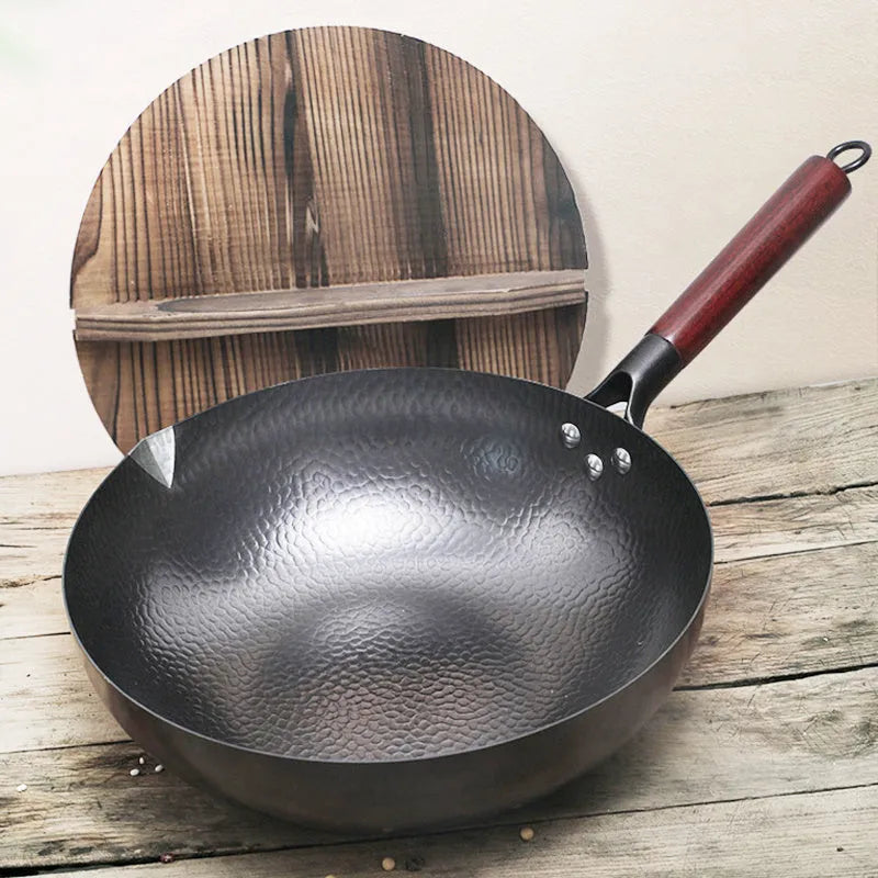 Traditional black iron wok with a long wooden handle on a kitchen counter.