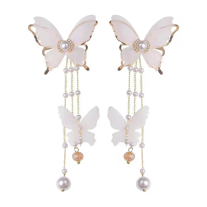 White butterfly-shaped earrings with lace detail, pearl tassels, and rhinestones on a copper alloy base.