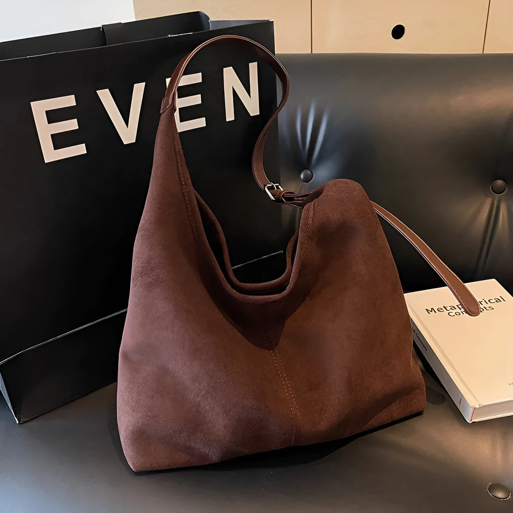 Women's suede bucket bag in black with stitching detail, single shoulder strap, and outer sandwich pocket