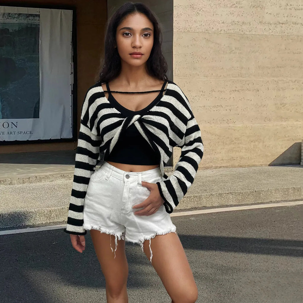 A woman wearing a cropped black and white striped long-sleeved sweater with a front and back exposed-navel design.