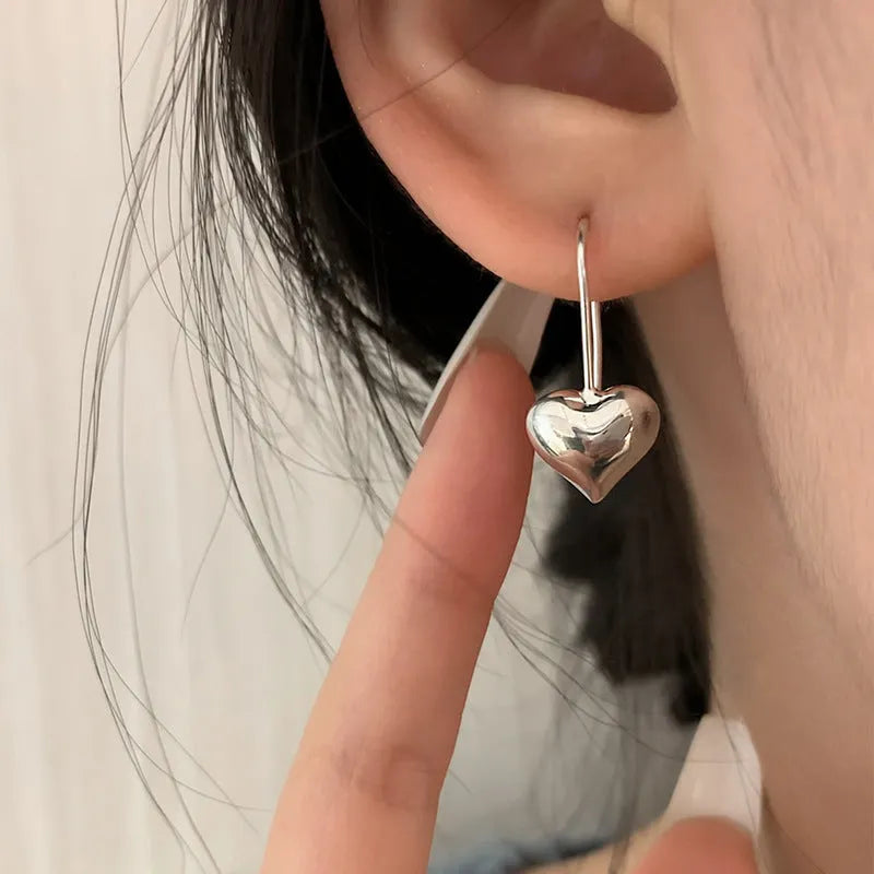 Silver Korean style heart-shaped earrings with a glossy three-dimensional design on a white background.