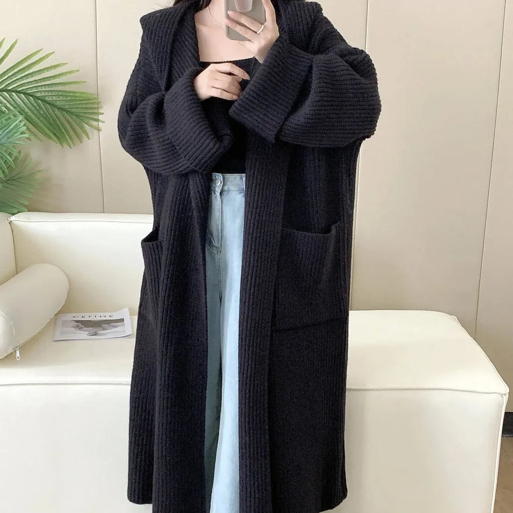 Woman wearing a long loose hooded cardigan coat in acrylic fabric, open as a cardigan.