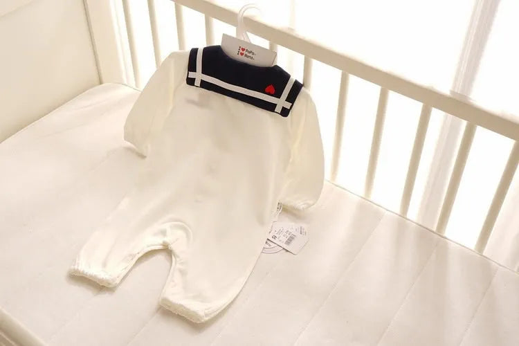 Navy blue Japanese style baby bodysuit with long sleeves and a detachable hood laid flat.