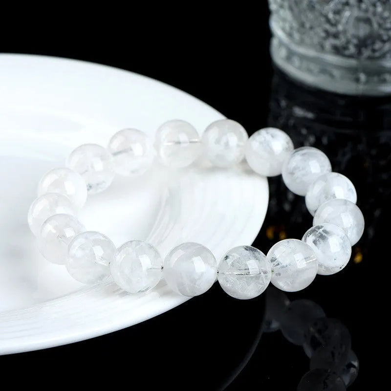 Women's natural blizzard snowflake round bead crystal bracelet with geometric design on a wrist.