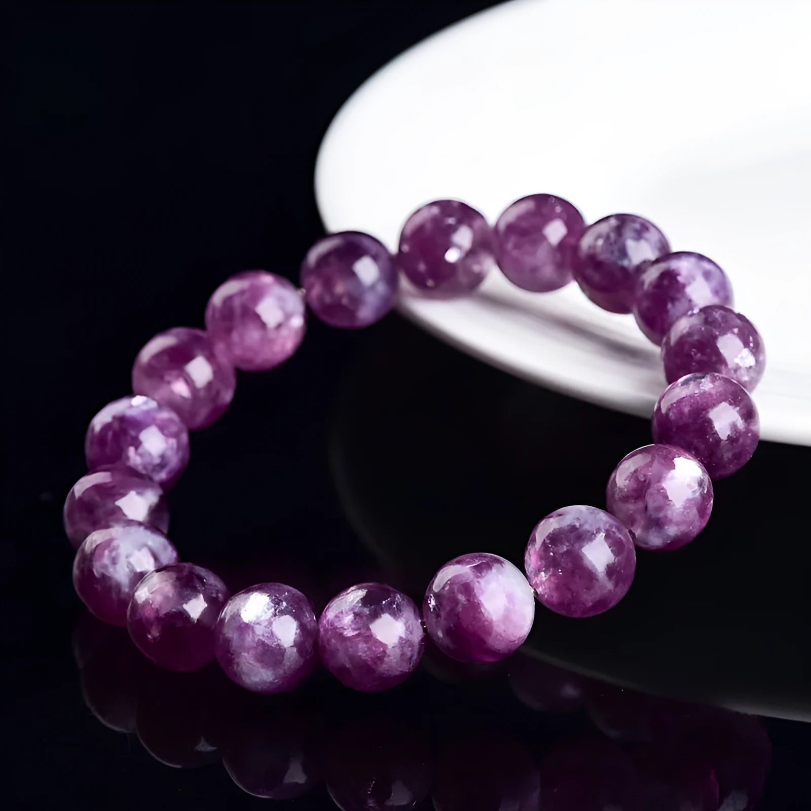 Geometric purple and pink polished crystal bracelet on a wrist, showing single strand of beads.