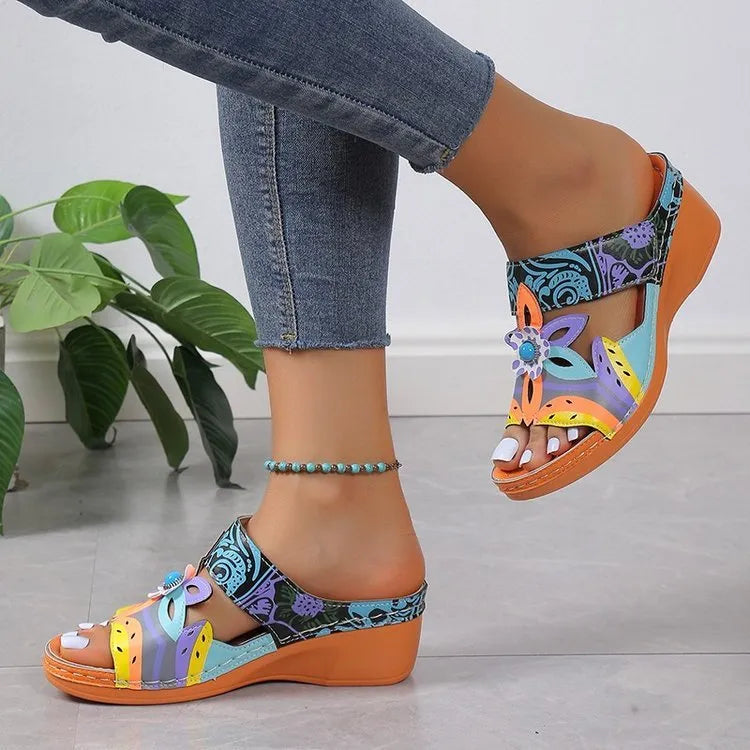 Women's leather sandals in orange with a round toe and rubber sole, shown from the side.