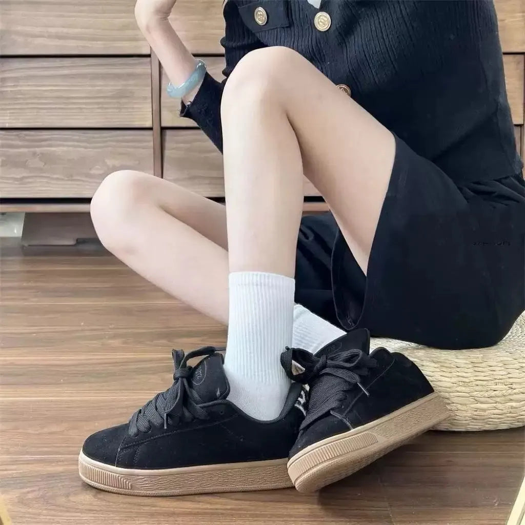 Black retro low-top sneakers with round toe and front lace-up closure on injection-moulded rubber sole