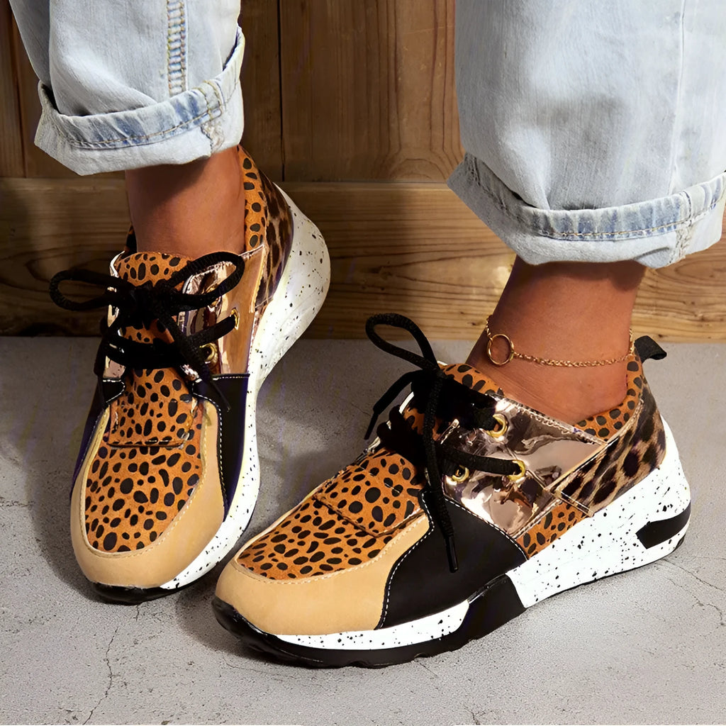 Women's suede sneakers with a wedge heel in leopard print, shown on a foot.