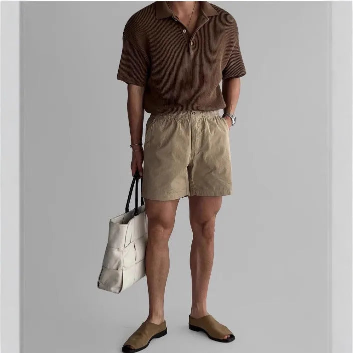 A pair of loose-fitting cotton sports shorts in khaki colour on a white background.
