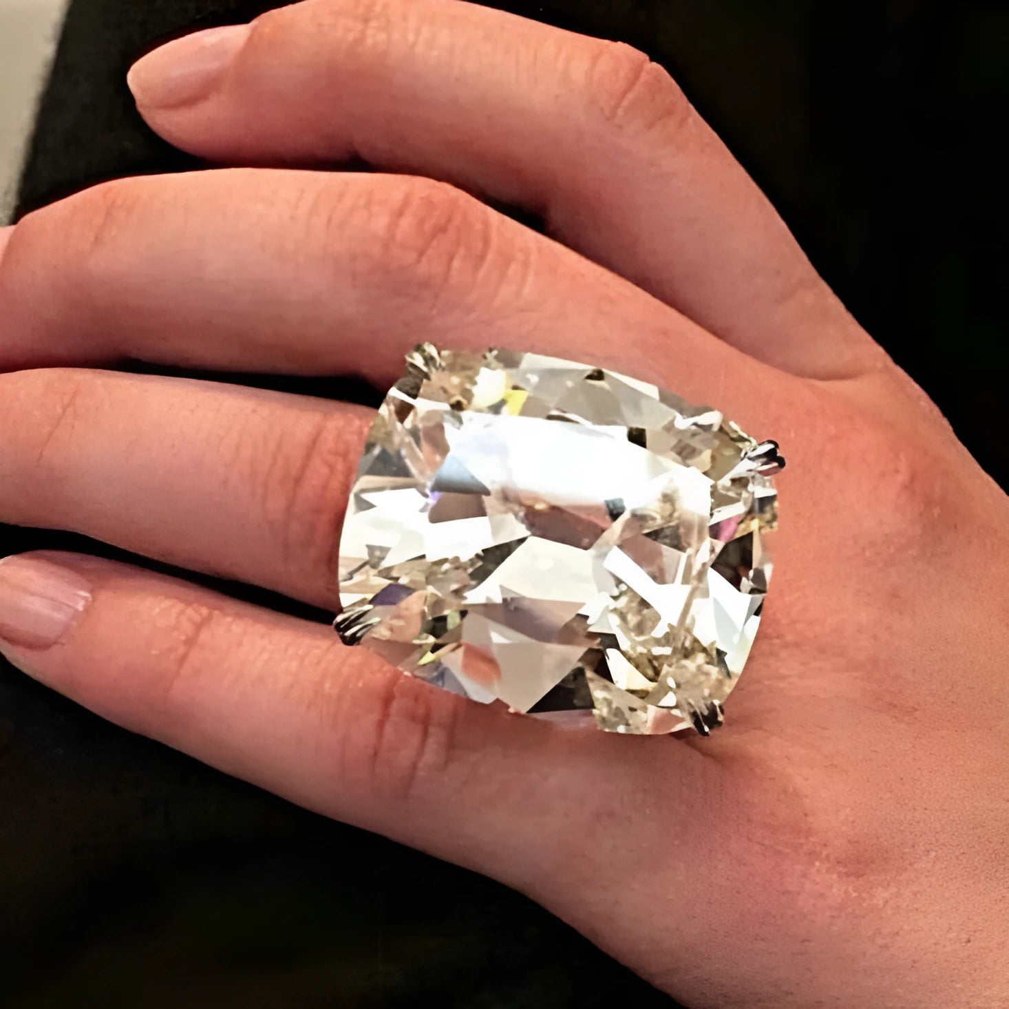 Simple white gold colour ring with an inlaid square diamond geometric design, shown on a model's hand.