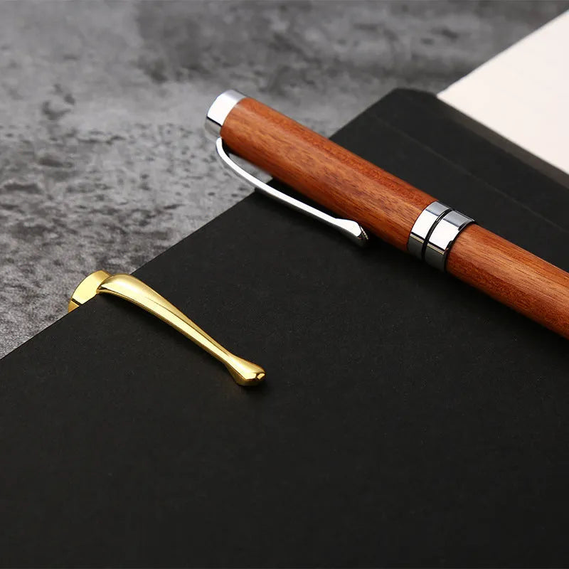 Gold metal and rosewood rollerball pen on a desk, 14cm long