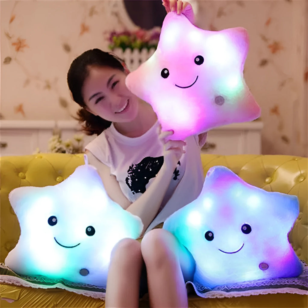 Colourful glowing five-pointed star plush pillow on a dark background, illuminated from within.