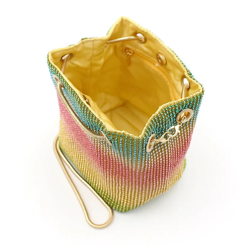 Soft rainbow rhinestone bucket handbag with adjustable strap on a white background.