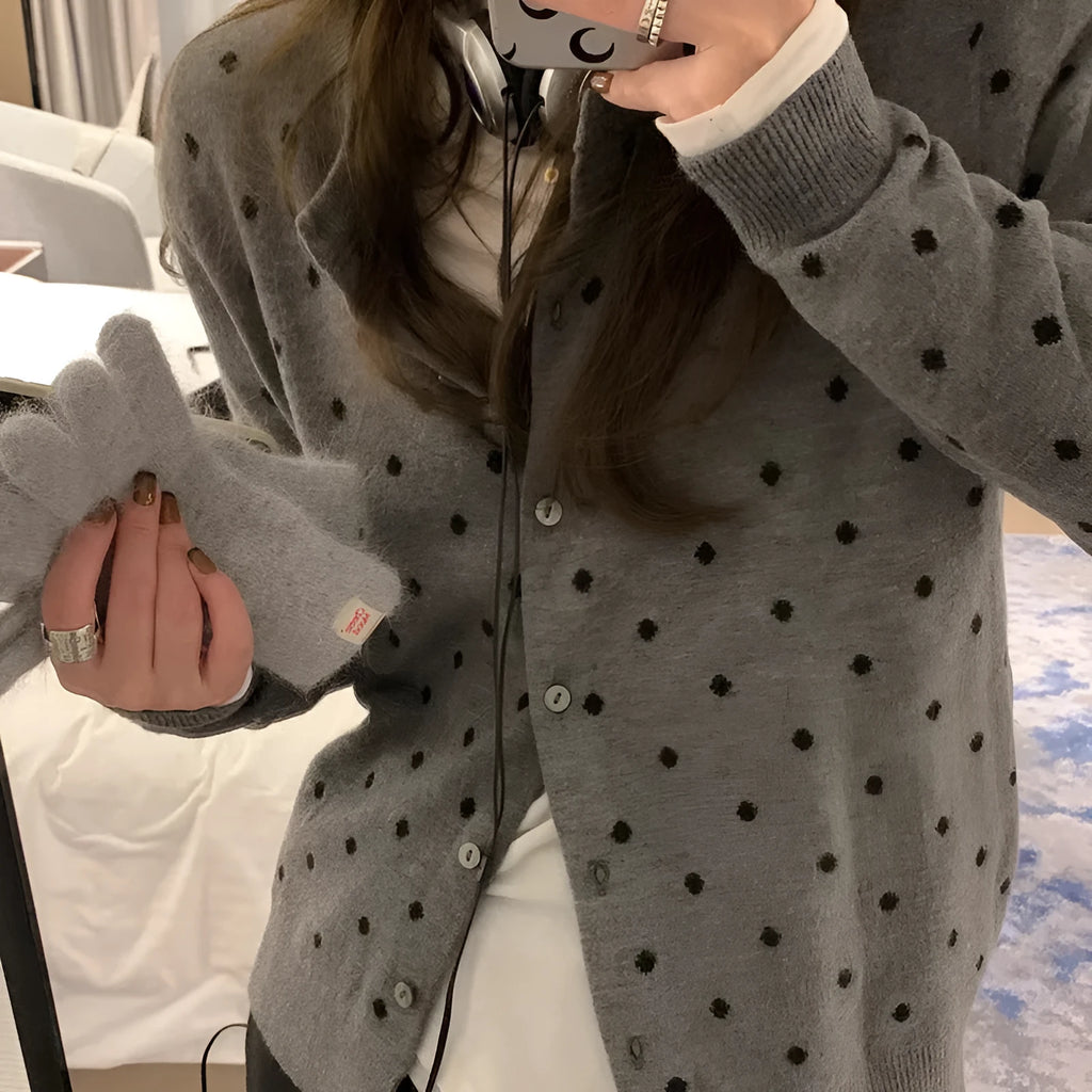 Grey dot pattern women's knitted cardigan with crochet flower detail on a hanger.
