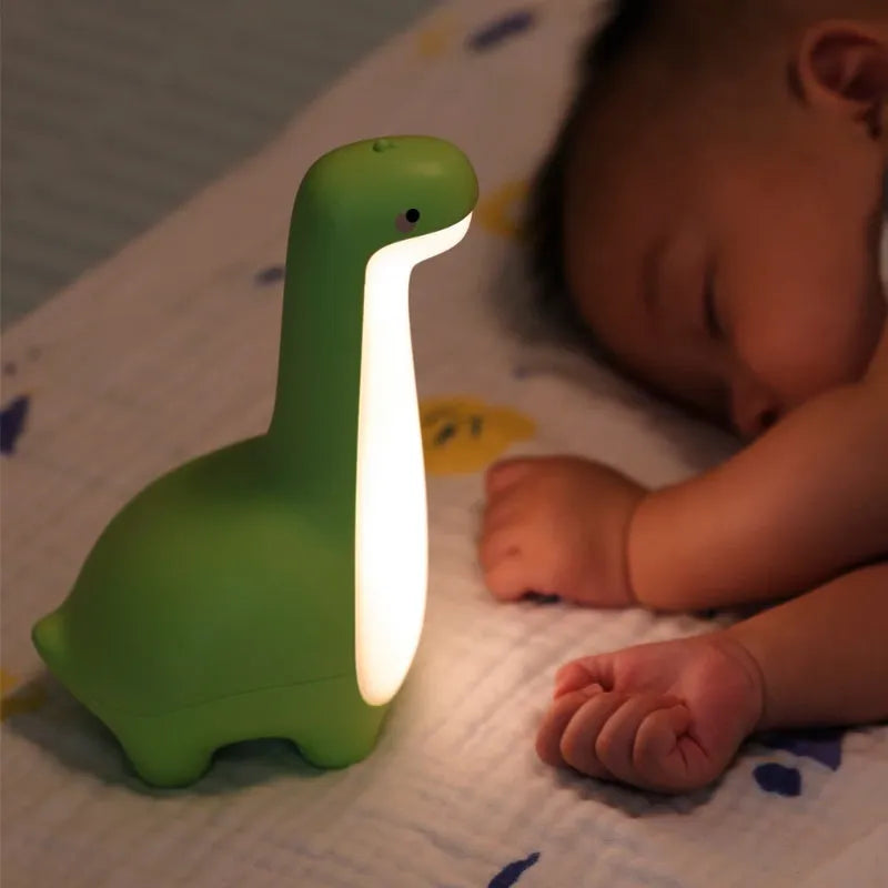 Dinosaur night light in lemon yellow with warm 3000K glow on a bedside table, USB charging cable included