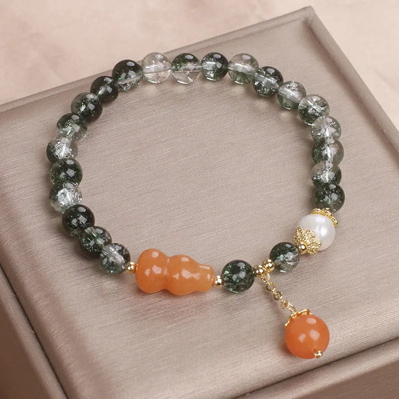 Green phantom quartz crystal bracelet with pearl and rhinestone accents on women's wrist