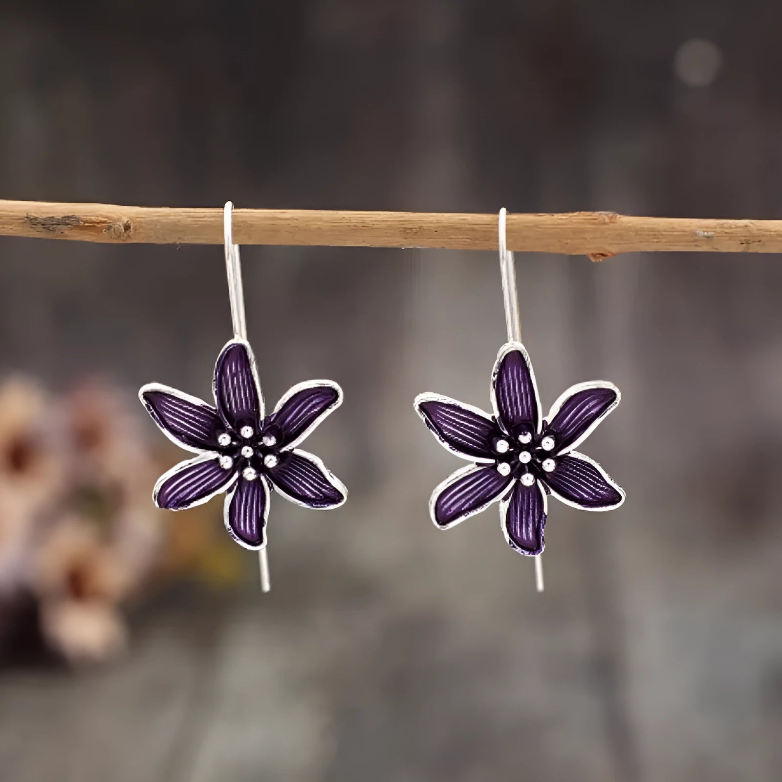 A pair of purple flower-shaped alloy earrings with an electroplated finish on a white background.