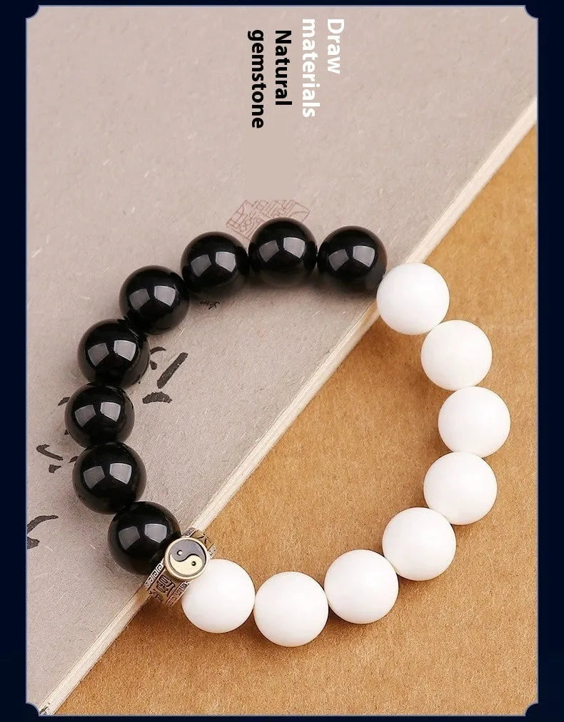 Black and white obsidian Tai Chi bracelet with geometric beads showing mantra inscriptions.