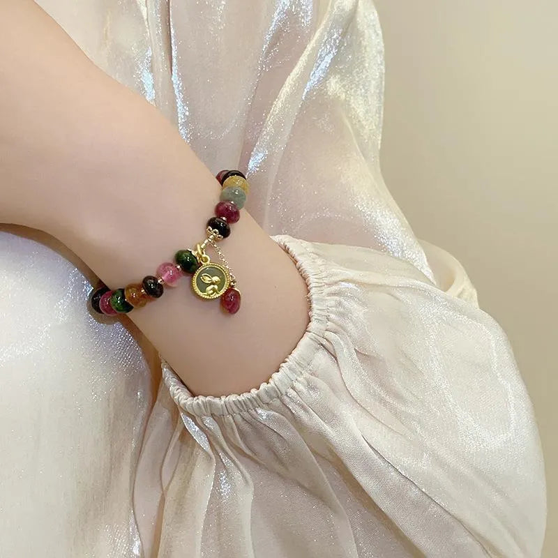 Close-up of a colourful tourmaline rabbit pendant bracelet with natural stone round beads.