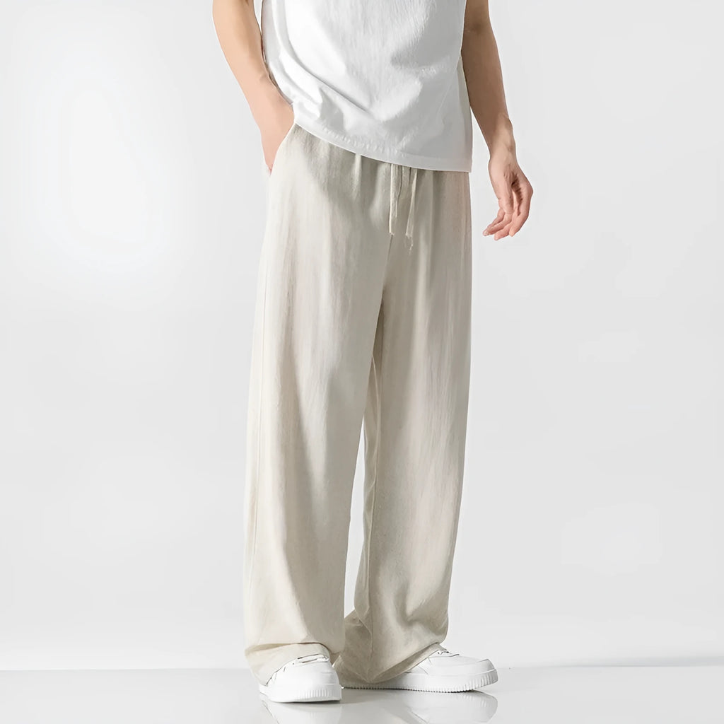 Man wearing beige loose-fit cropped straight-leg trousers made from bamboo fibre with a drawstring waist.