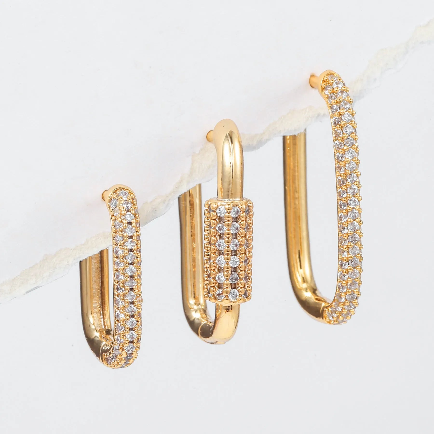 Three geometric copper earrings with inlaid zircon on a square clip, in gold and white finishes.
