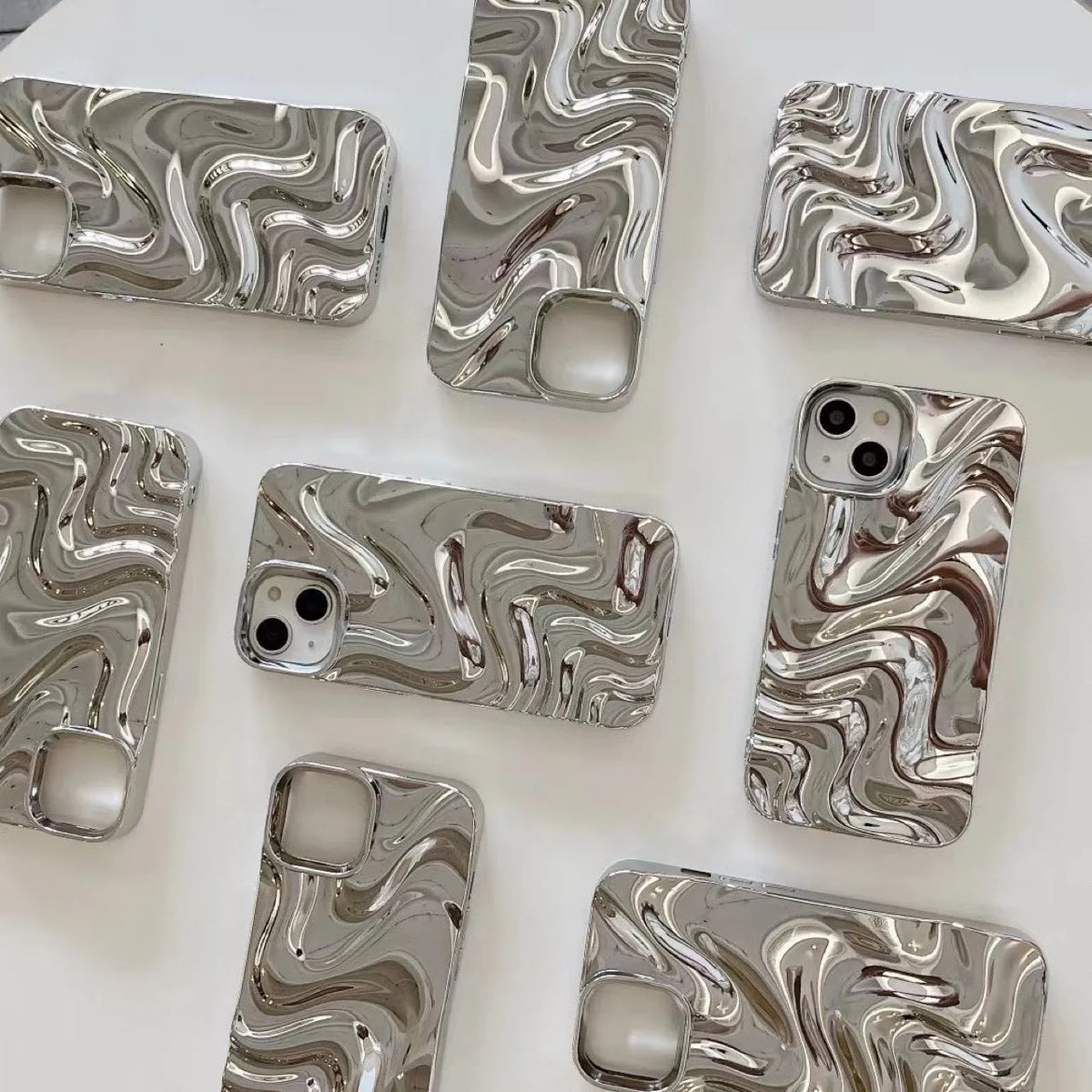 Three-dimensional pleated water ripple TPU phone case for iPhone 14 in glossy silver, showing textured back and edge coverage