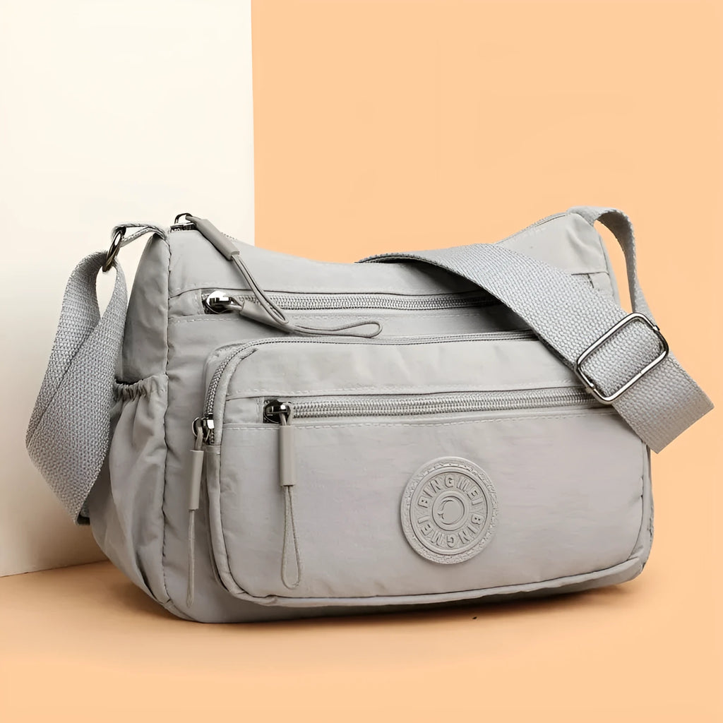 Soft water-repellent nylon crossbody bag in black with an outer pocket and zipped main compartment.