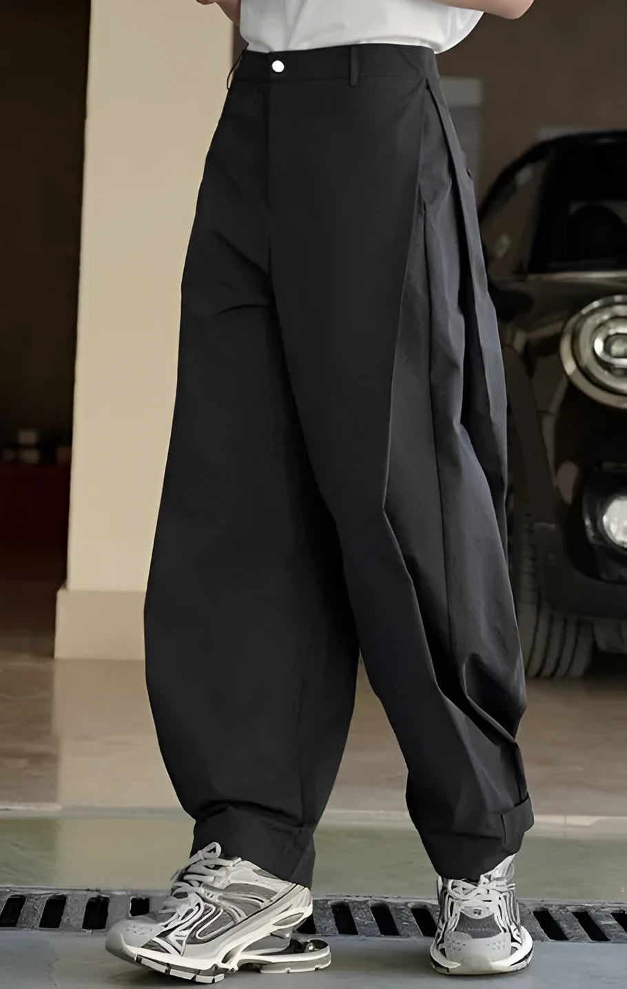Black high-waisted wide-leg trousers with front pleats on a model, showing the loose fit.
