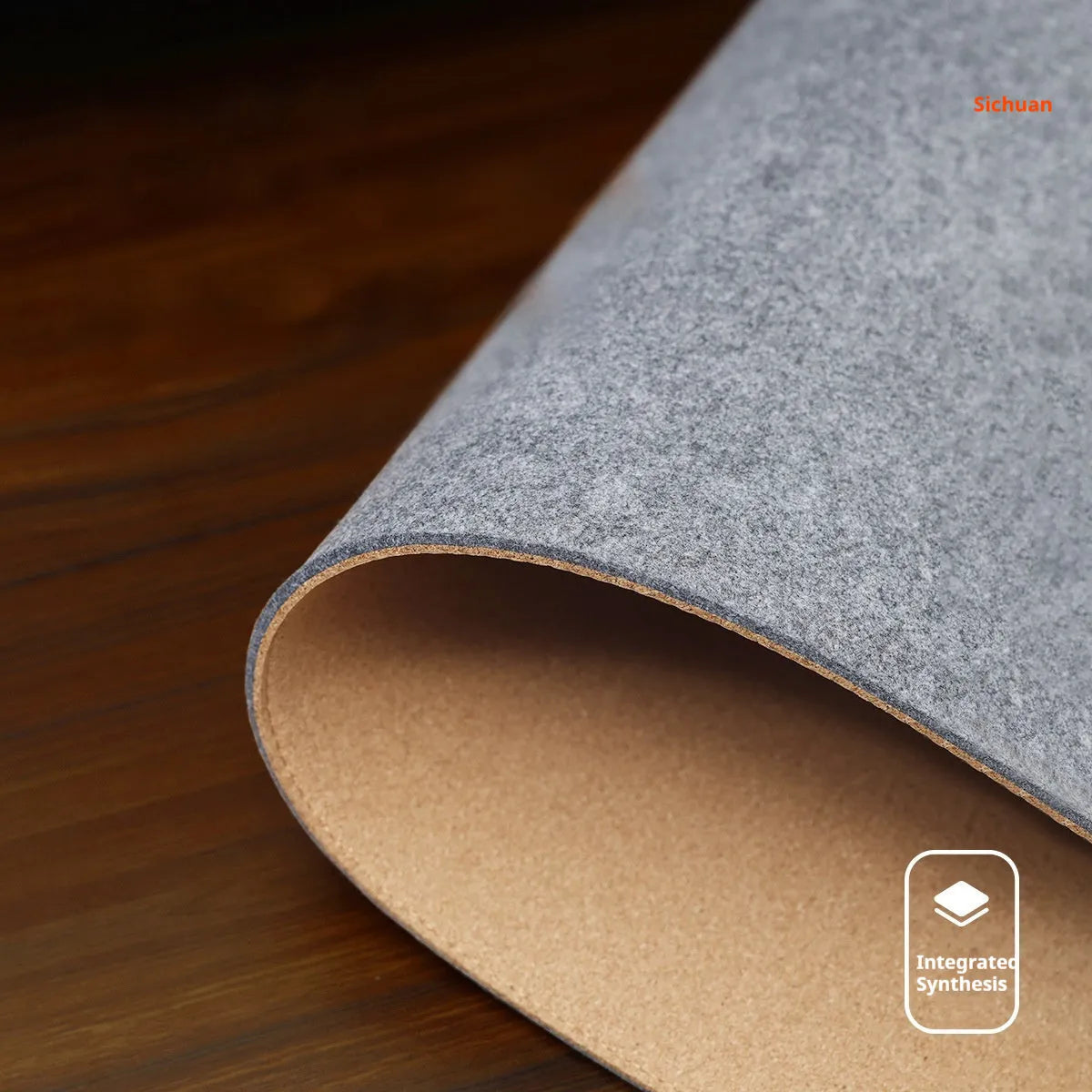 Oversized black and gray felt desk mat with cork base on a wooden desk