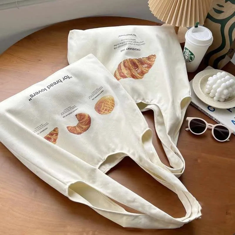 Beige canvas shoulder tote bag with a decorative bread and croissant print design.